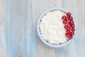 An overhead photo of fresh natural cottage cheese with red currant in a blue ceramic bowl on the wooden table. Organic eco healthy Royalty Free Stock Photo