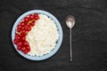 An overhead photo of fresh natural cottage cheese with spoon, red currant in a blue ceramic bowl on the black stone plate. Organic Royalty Free Stock Photo