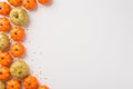 Overhead photo of heap of orange mini and golden shine pumpkins with confetti isolated on the white background with copyspace