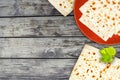 An overhead photo of Jewish Matzah bread on the ceramic plate on the grunge table. Matzah and spring linden tree branch for Jewish