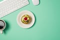 Overhead photo of keyboard computer mouse cup of coffee and plate with fruit cake isolated on the teal backdrop Royalty Free Stock Photo