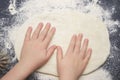 An overhead photo of kid`s hands, some flour, wheat dough and rolling pin on the black table with a place for text. Children hand Royalty Free Stock Photo