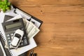 Overhead photo of notebook clipboard calculator car toy black pen money dollars and plant isolated on the wooden backdrop Royalty Free Stock Photo
