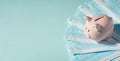 Overhead photo of piggybank pink pig with pile of masks on the blue background