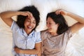 Overhead Portrait Of Loving Same Sex Female Couple Wearing Pyjamas Lying On Bed At Home