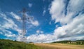 Overhead power line pylon in summer landscape with blue sky and puffy white clouds Royalty Free Stock Photo