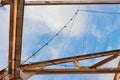 Overhead rusted steel trusses and strings of light before a blue sky with clouds