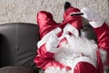 Overhead of Santa Claus relaxing in sofa at home Using cell phone for communication and leisure. Having a videocall or taking a s Royalty Free Stock Photo