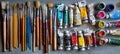 Overhead shot of an assortment of paintbrushes and tubes of paint on a flat gray surface Royalty Free Stock Photo