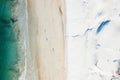 Overhead shot of a beach where the sand meets the snow from the mountains