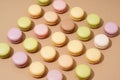 overhead shot of a beige table surface featuring an array of colorful macarons in neat rows