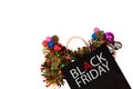 Overhead shot of black paper bag with black friday word and christmas decorations on white background.