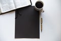 Overhead shot of a black rectangle on a white surface near a Bible, coffee and a pen Royalty Free Stock Photo