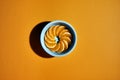 Overhead shot of a blue round container with circular shaped mandarin segments on a flat orange background