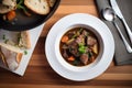 overhead shot of a bowl of beef bourguignon with crusty bread
