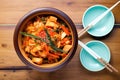 overhead shot of a bowl of kimchi on a wooden table with chopsticks