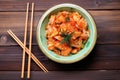 overhead shot of a bowl of kimchi on a wooden table with chopsticks