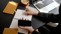 Overhead shot of businesswoman writing on notebook while using smartphone in comfortable workplace Royalty Free Stock Photo