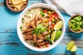 overhead shot of carnitas burrito bowl with rice and beans