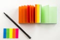 Overhead shot of colorful notepad, sticky note strips and a black pen on a white surface Royalty Free Stock Photo