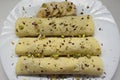 Overhead shot of 3 crepes pancakes with bananas topped with chocolate and cocos shavings and pistachios on a white plate Royalty Free Stock Photo