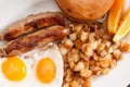 Overhead shot of eggs with English banger sausages and hashbrowns and a bagel