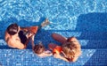 Overhead Shot Of Family With Young Son Putting On Armbands For Swimming Lesson In Outdoor Pool