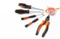 Overhead shot of a four screw drivers, a plier and a measuring tape on a white background