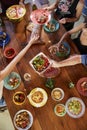 Overhead shot of friends passing food across a dinner table