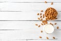 Overhead shot of glass of almond milk on white wooden background with almonds in bowl and copyspace