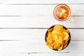 Overhead shot of glass of beer and potato chips in bowl on wooden table. Royalty Free Stock Photo