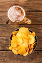 Overhead shot of glass of beer and potato chips in bowl on wooden table Royalty Free Stock Photo