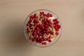 Overhead shot of a glass bowl of vanilla yogurt with currants on top on a beige background