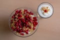 Overhead shot of a glass bowl of vanilla yogurt with currants on top on a beige background