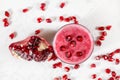 Overhead shot - glass with pomegranate smoothie, fruit berries scattered over white desk around