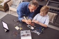 Overhead Shot Of Grandson With Grandfather Assembling Electronic Components To Build Robot At Home