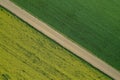 Overhead shot of a large farming field with a narrow road in the middle during daytime