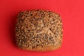 Overhead shot of a loaf of brown bread with sesame seeds isolated on a red background Royalty Free Stock Photo