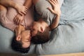 Overhead Shot Of Loving Same Sex Male Couple Lying On Bed At Home Hugging And Kissing Together