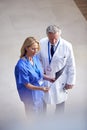 Overhead Shot Of Male Doctor Wearing White Coat Discussing Scan With Female Colleague In Scrubs Royalty Free Stock Photo