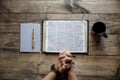 Overhead shot of male`s hand near an open book and coffee mug on a wooden surface Royalty Free Stock Photo