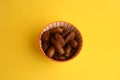 Overhead shot of Medjool dates on in a decorative bowl on a yellow table