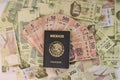 Overhead shot of a Mexican passport a heap of colorful pes banknotes