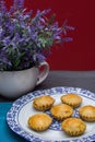 An overhead shot of mini pies in a china plate next to a white vase full of lavender