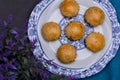 An overhead shot of mini pies in a china plate next to a white vase full of lavender