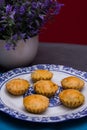 An overhead shot of mini pies in a china plate next to a white vase full of lavender