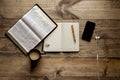 Overhead shot of a notebook with a fountain pen near an open book and smartphone on wooden table Royalty Free Stock Photo