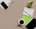 Overhead shot of office desktop. Telephone, tea cup, glasses, pencils, notebook, pen, potted plant on light background.Top view Royalty Free Stock Photo