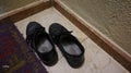 Overhead shot of a pair of worn male black shoes placed next to s small carpet