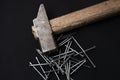 Overhead shot of a pile of steel nails and a hammer with a wooden handle on a black background Royalty Free Stock Photo